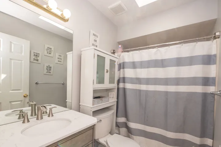Bathroom featuring a vanity with a white countertop and undermount sink, brushed nickel fixtures, a full-width mirror, and overhead lighting
