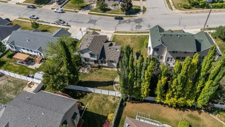 Spacious rear yard featuring mature trees, a white perimeter fence, and ample green space