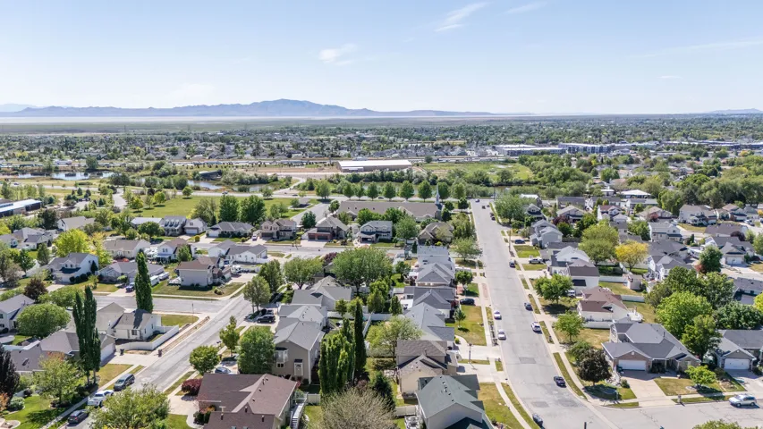 Aerial perspective showcasing a residential neighborhood with tree-lined streets, varied architectural styles, and distant mountain ranges