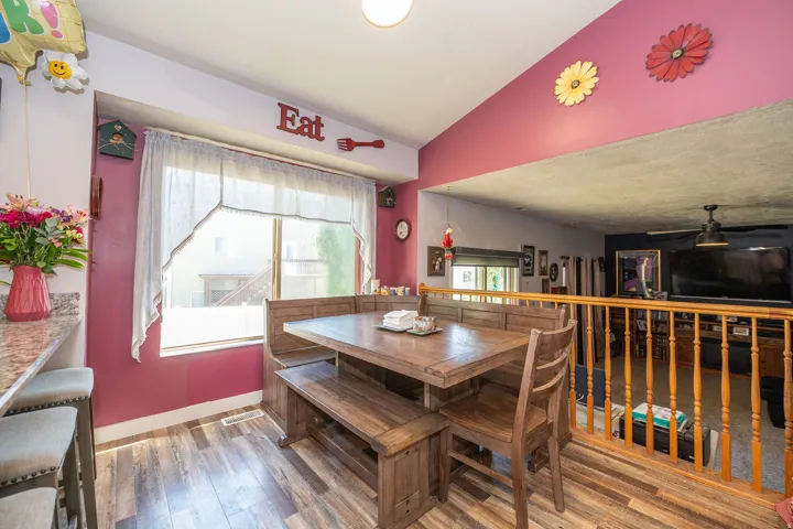 Kitchen dining nook featuring wood-finish flooring, a built-in wooden banquette, and a window providing natural light