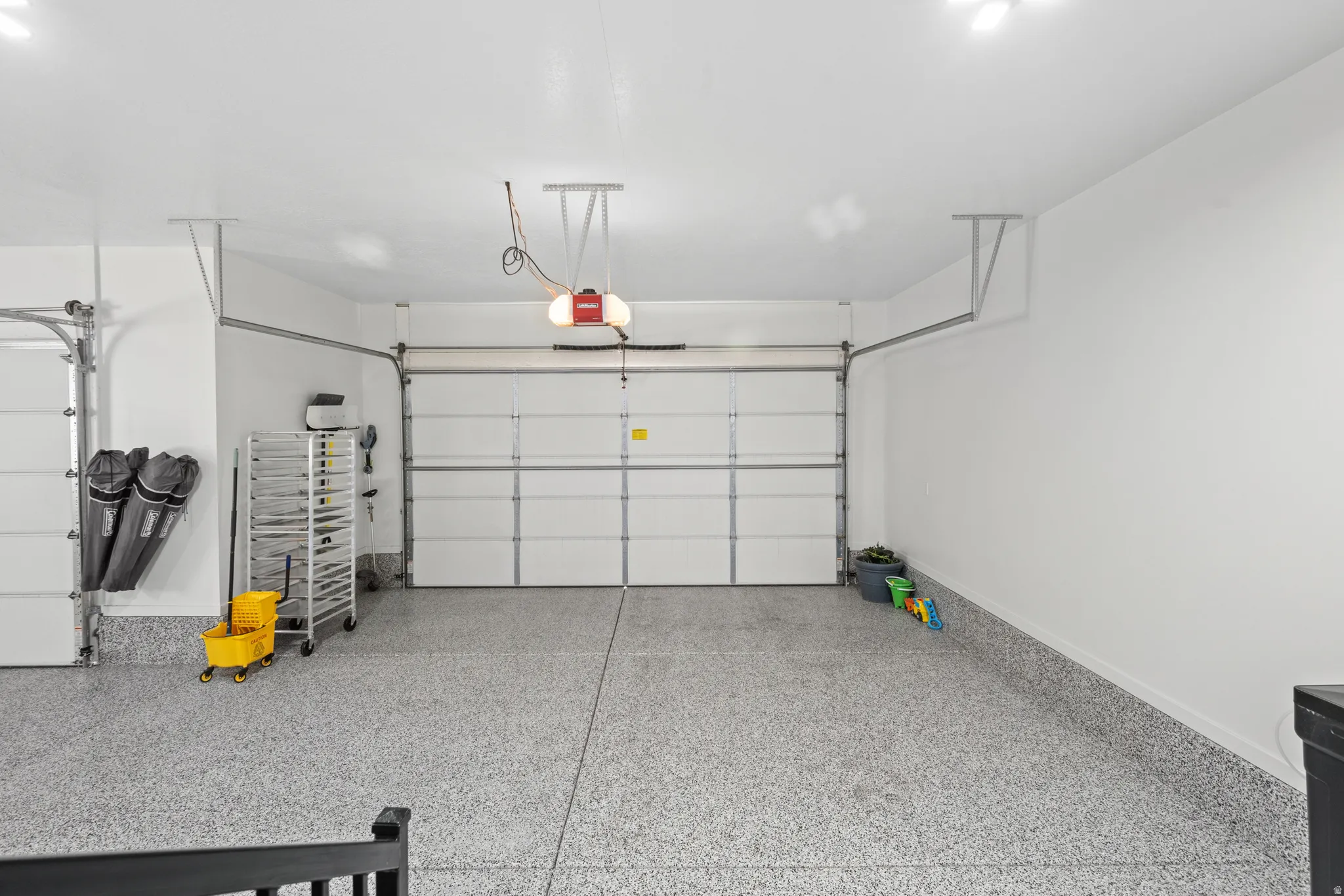 Two-car garage featuring an epoxy floor finish, two overhead garage doors with automatic openers, and recessed lighting