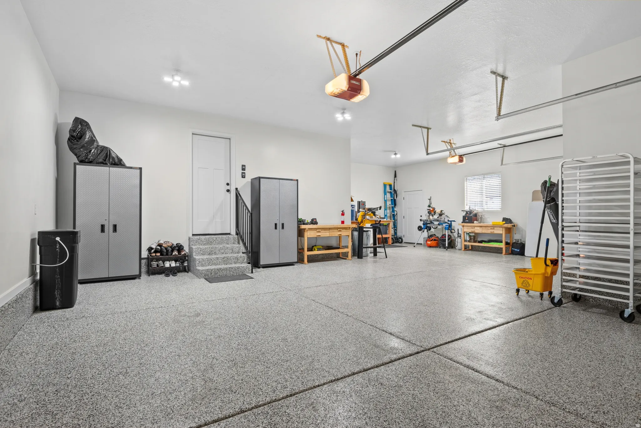 Spacious garage featuring a durable epoxy-coated floor, bright overhead lighting, and multiple windows providing natural illumination