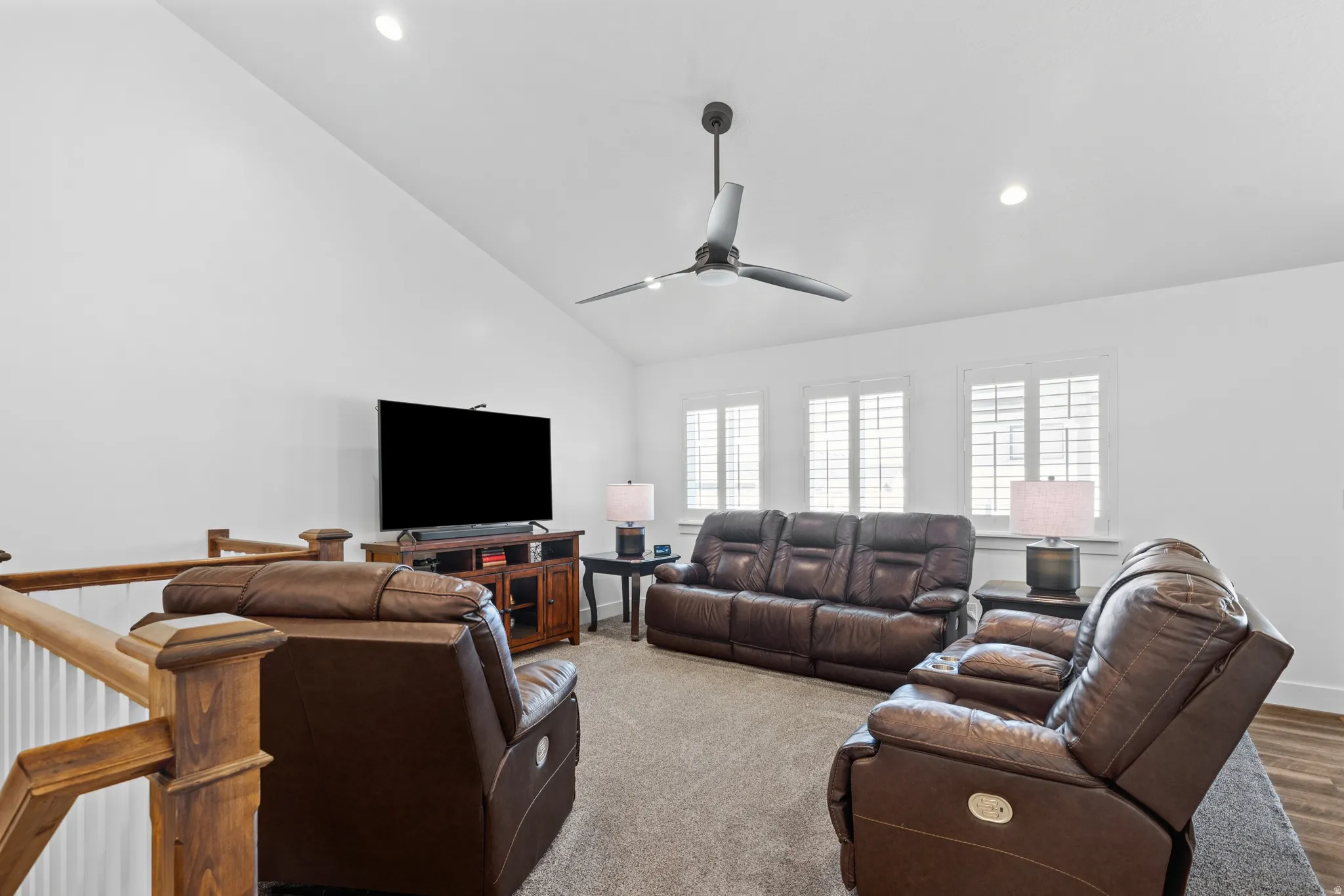 Loft area featuring vaulted ceilings, recessed lighting, a contemporary ceiling fan, and multiple windows with plantation shutters