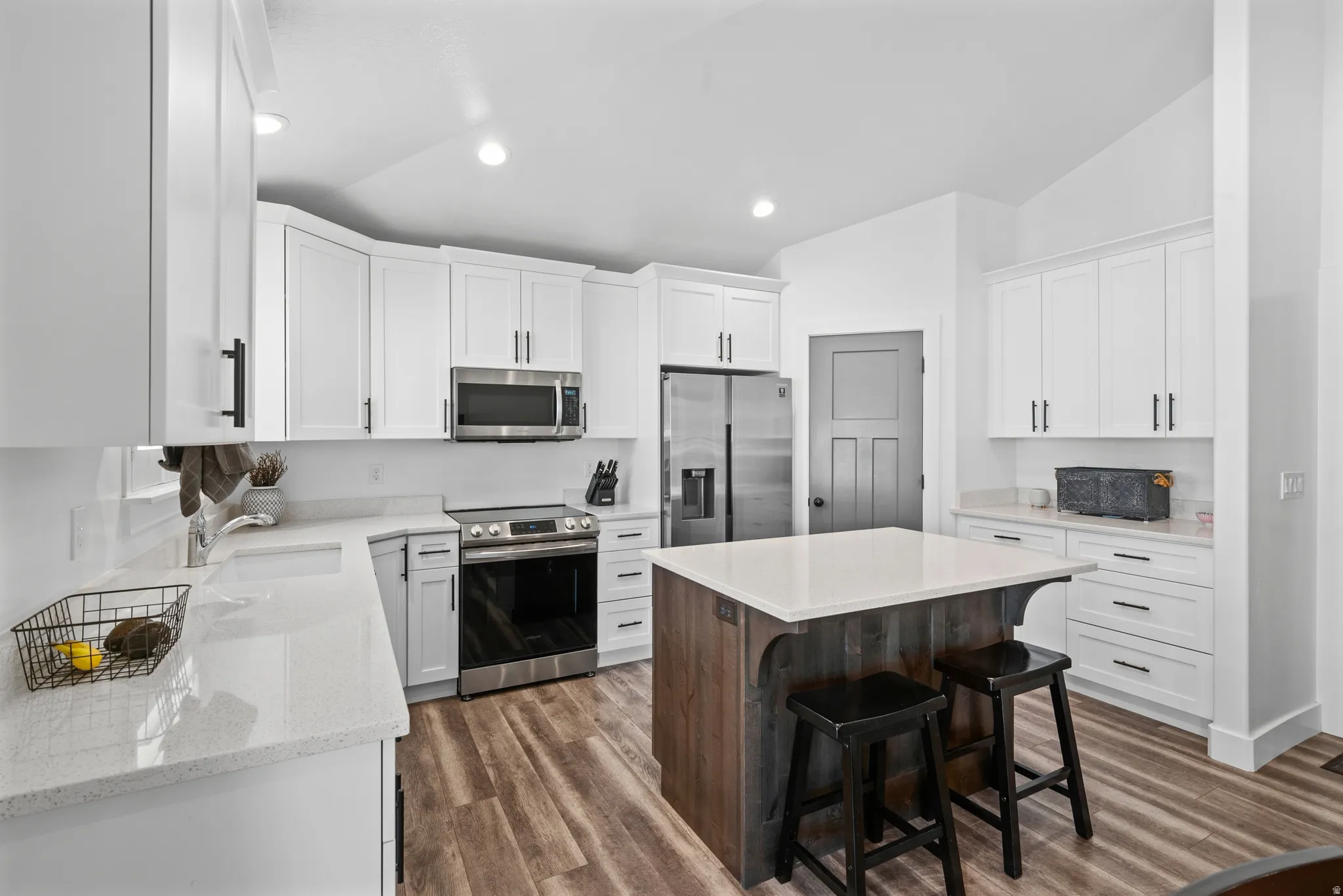 Modern kitchen featuring wood-finish flooring and a central island with a white countertop