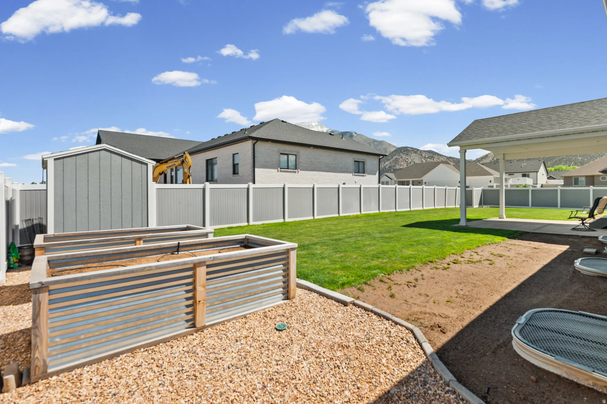 Expansive backyard featuring a manicured lawn, gravel landscaping, and two built-in corrugated metal planters
