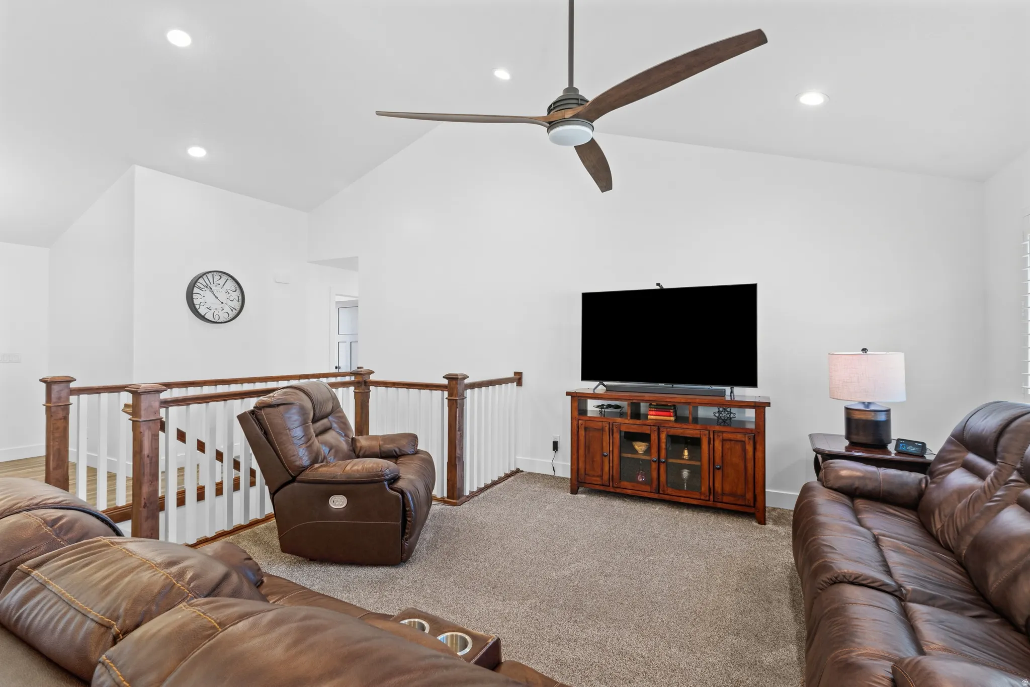 Carpeted living area featuring a vaulted ceiling with a contemporary ceiling fan, recessed lighting, and a wood-finish media console