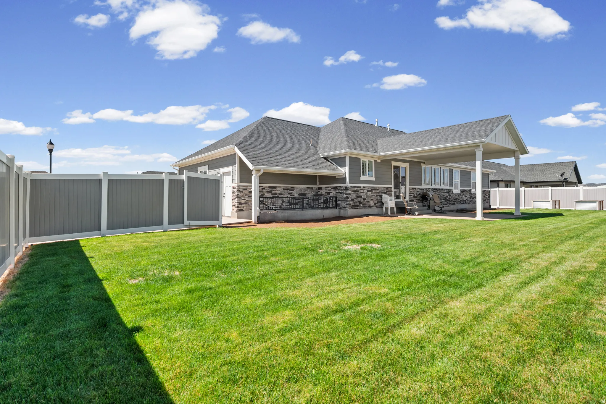 Expansive green lawn bordering a modern home with a covered patio