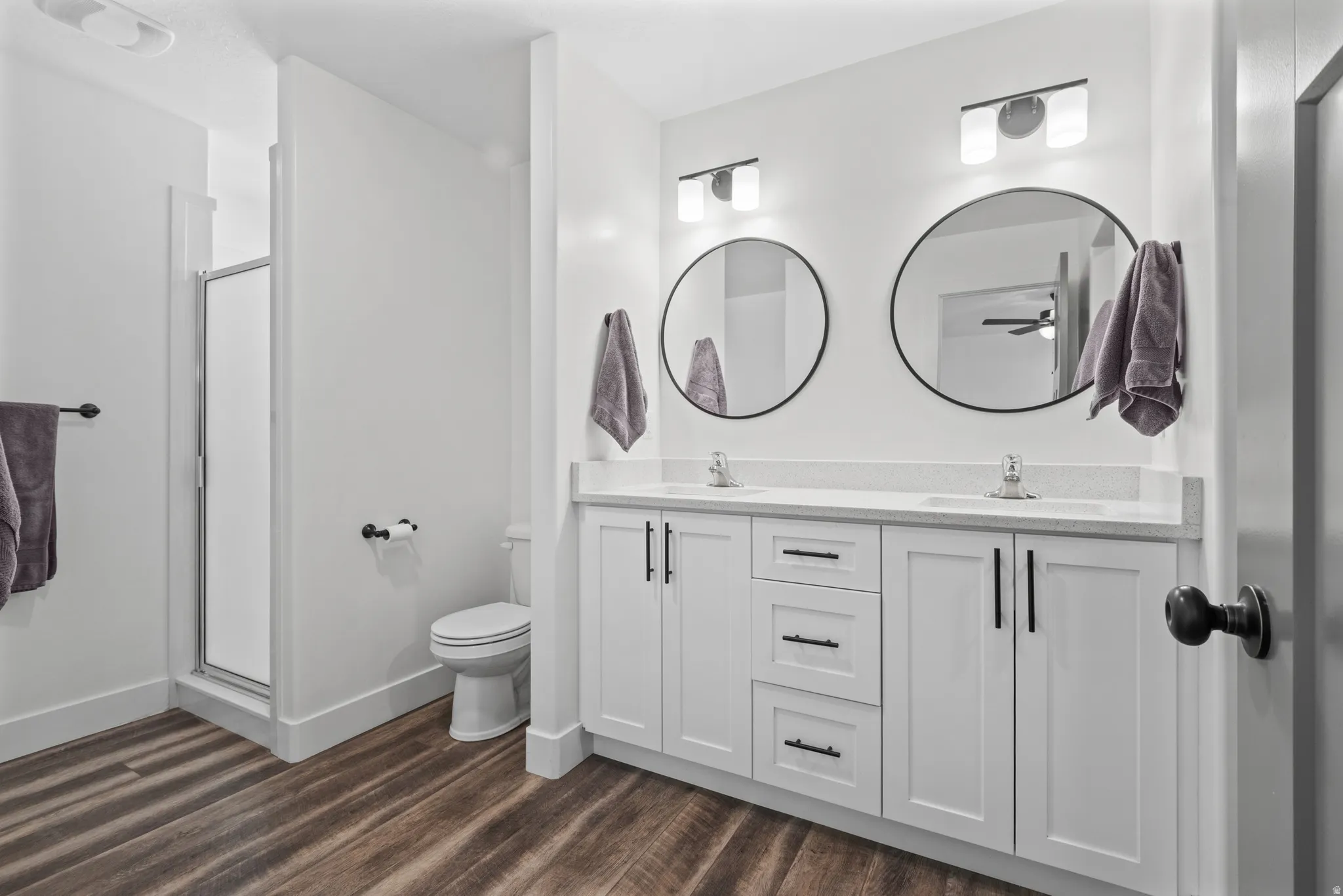 Dual vanity featuring white shaker cabinetry, light-toned countertops, and matte black hardware