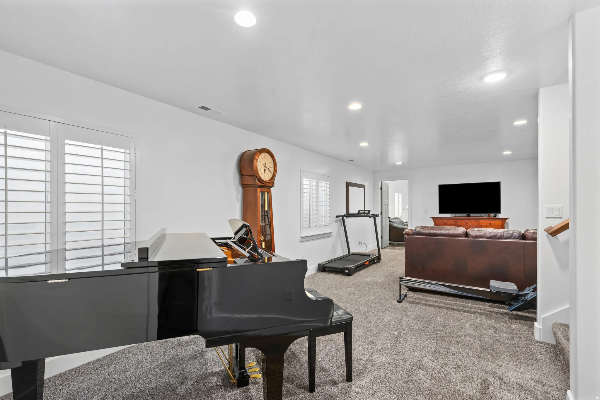 Spacious lower-level room featuring recessed lighting, white walls, and plush carpet flooring