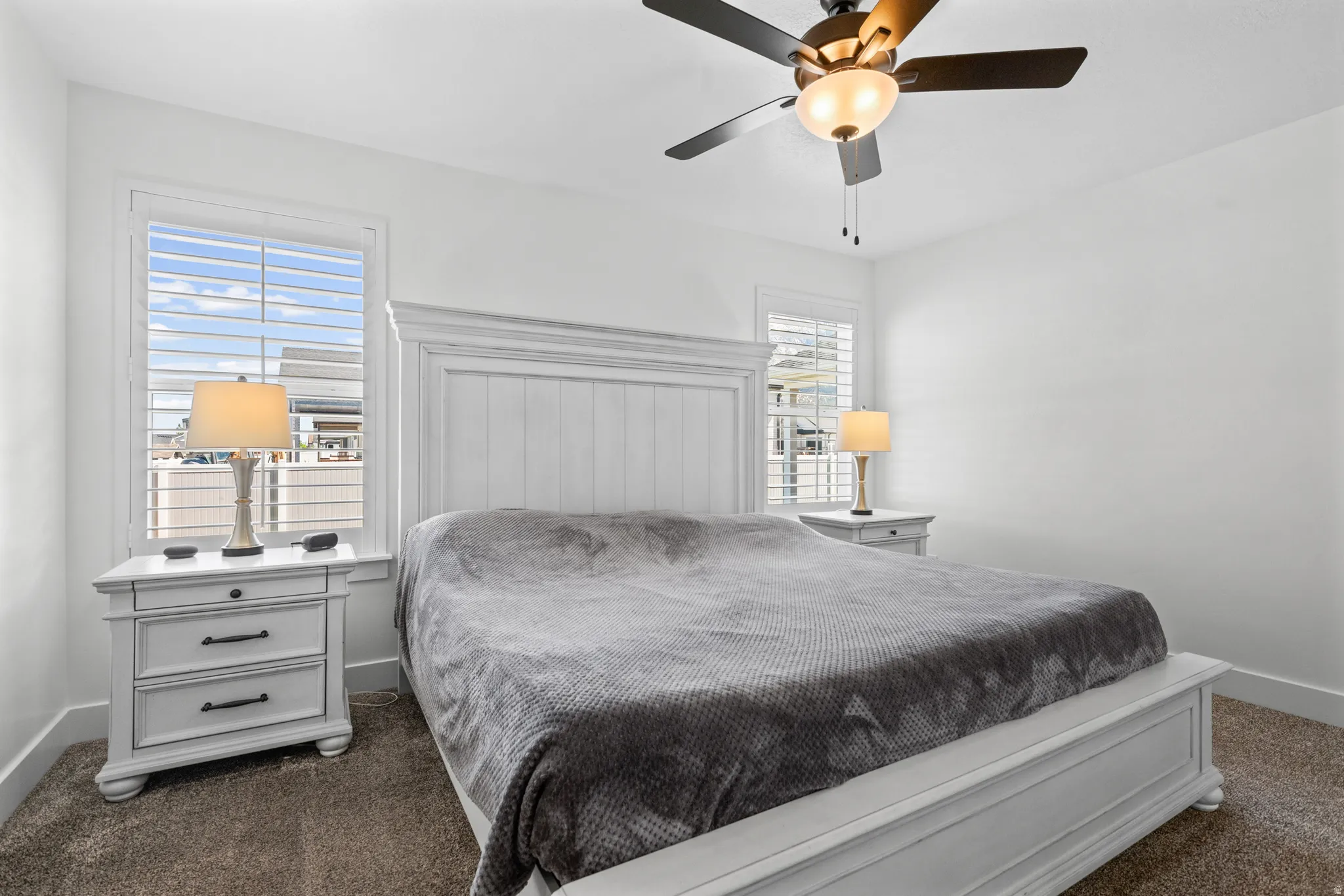 Bedroom featuring neutral-toned carpeting, white walls, and a ceiling fan with integrated lighting