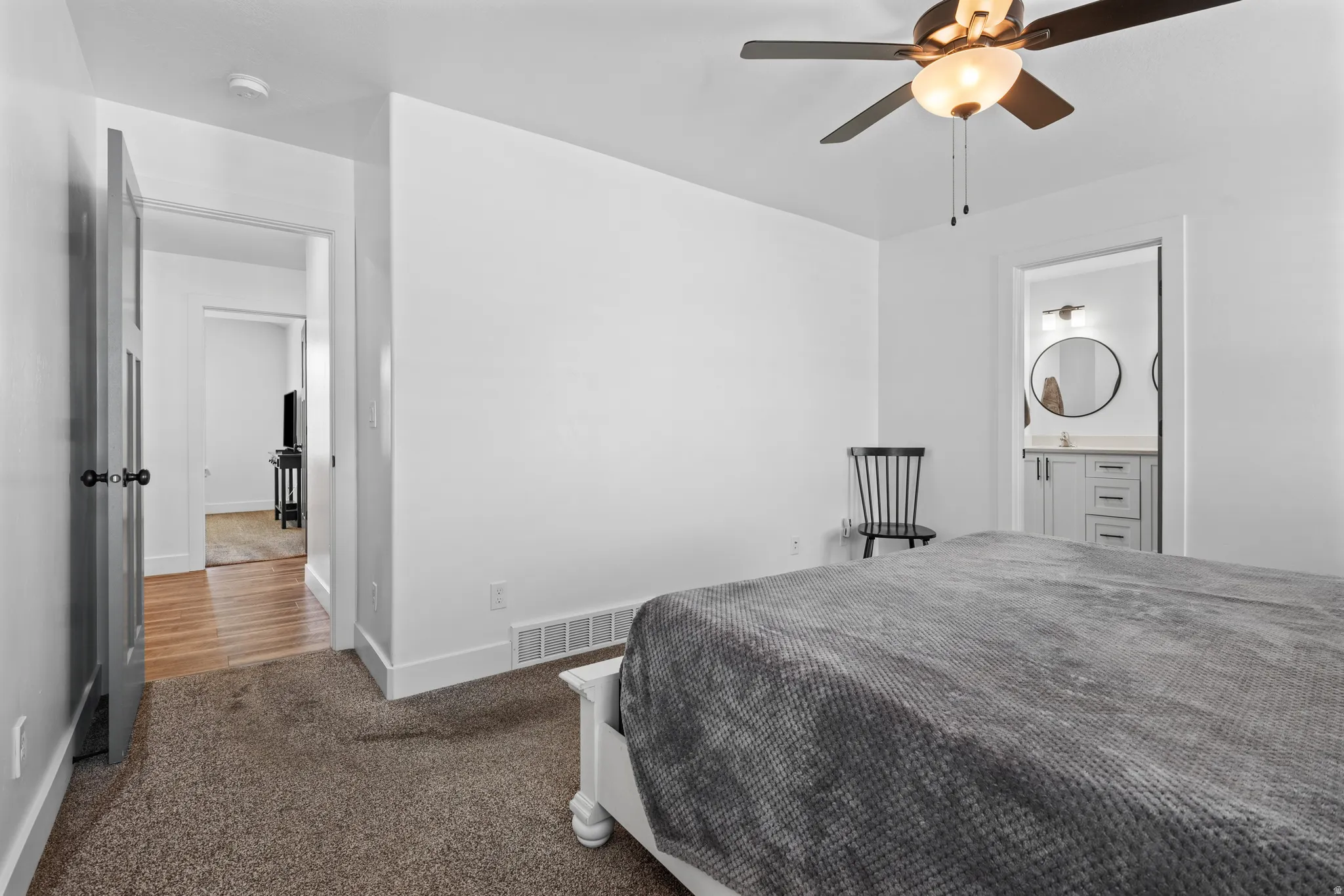 Carpeted room with a ceiling fan light fixture and white baseboards