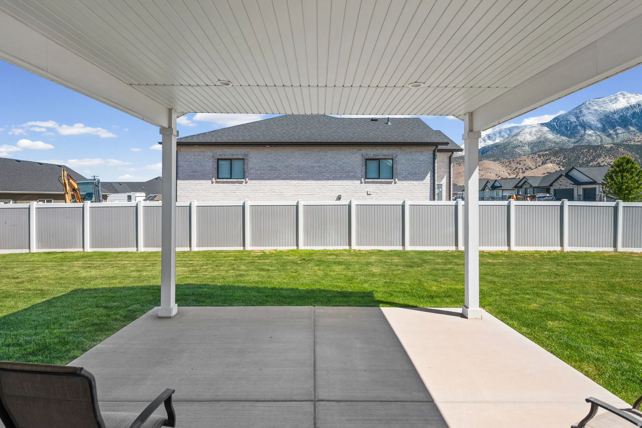 Covered concrete patio opening to a spacious lawn