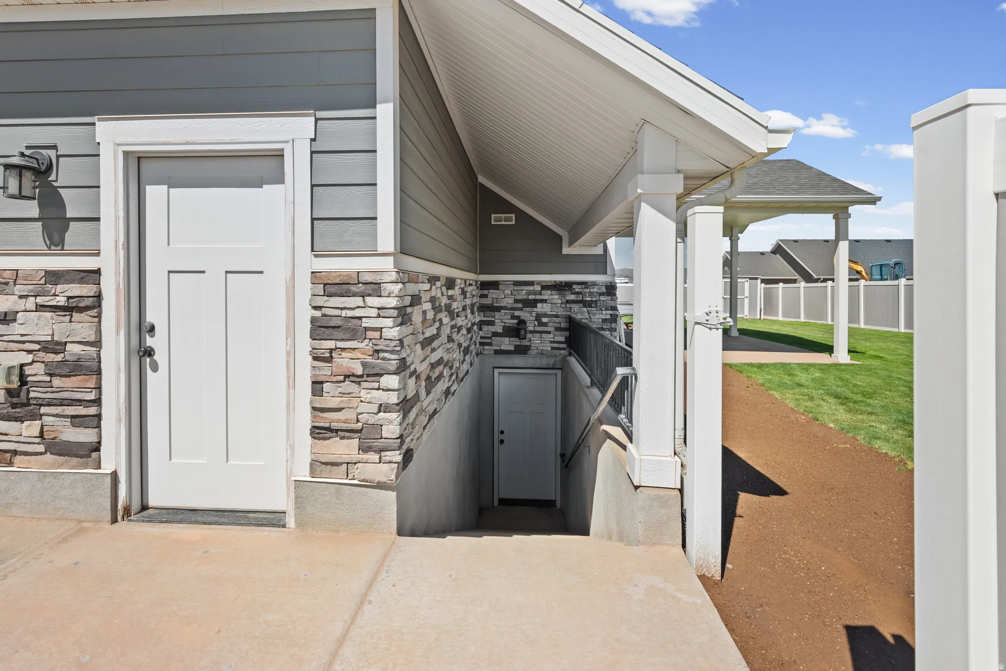 Exterior entrance featuring a white panel door, stone veneer detailing, horizontal siding, overhead lighting fixture, and covered entry