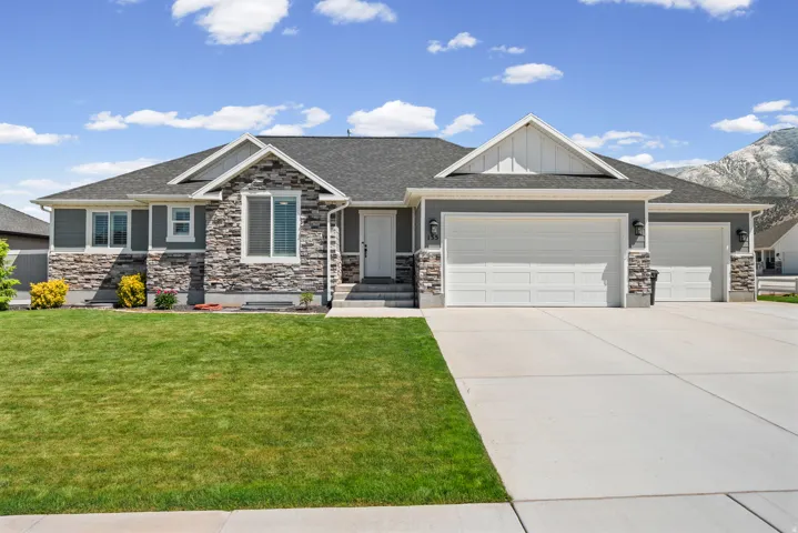 Ranch-style residence featuring a prominent stone facade, gray siding, and a dark shingle roof