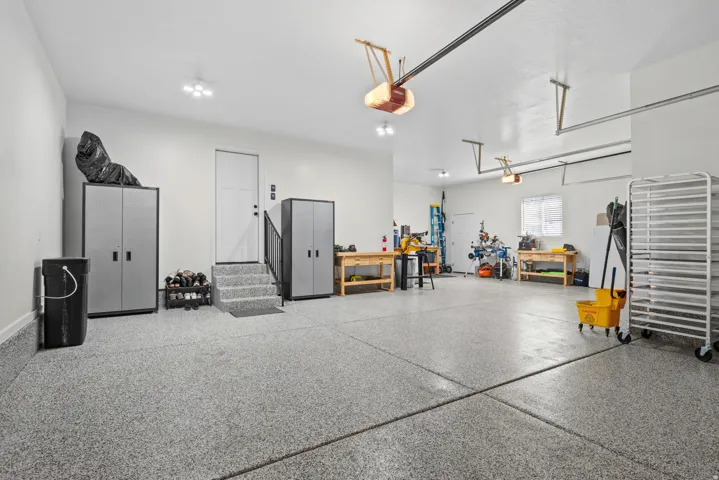 Spacious garage featuring a durable epoxy-coated floor, bright overhead lighting, and multiple windows providing natural illumination