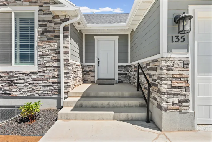 Stone veneer and siding exterior featuring a multi-level concrete entry, dark house numbers, an exterior lantern light fixture, and a white entry door