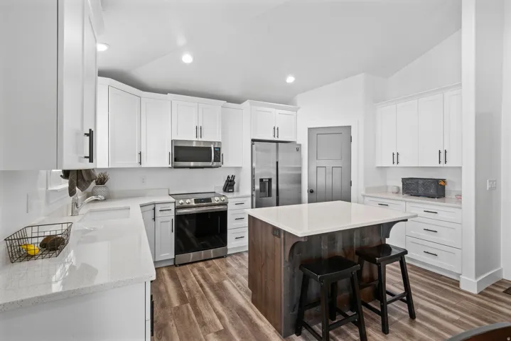 Modern kitchen featuring wood-finish flooring and a central island with a white countertop