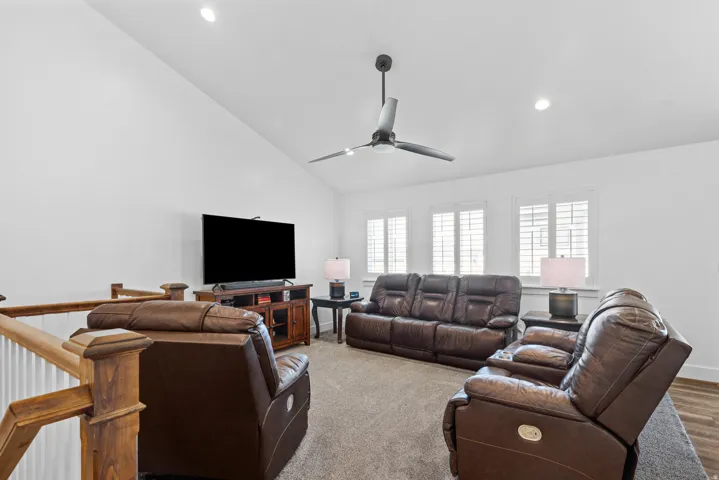 Loft area featuring vaulted ceilings, recessed lighting, a contemporary ceiling fan, and multiple windows with plantation shutters