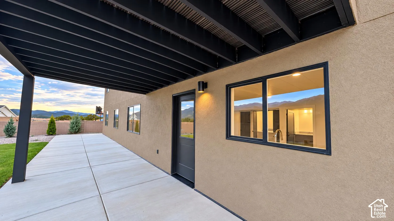 Covered patio with concrete slab, stucco exterior, and black frame windows