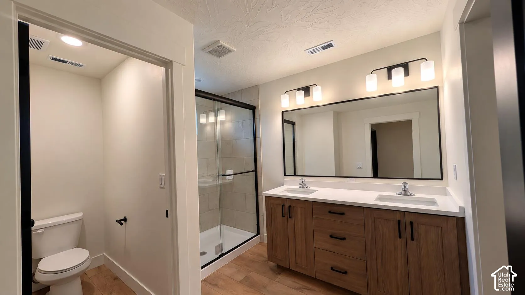 Double vanity with white countertops, undermount sinks, and wood-finish cabinetry