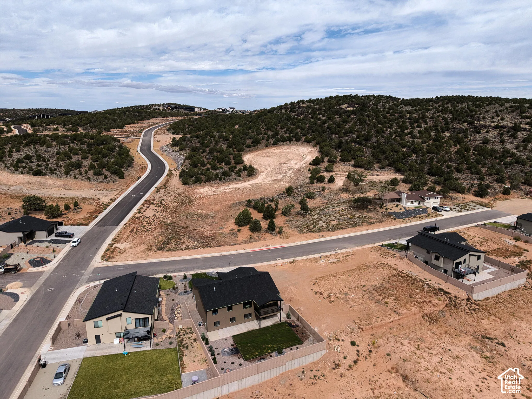 Expansive rural landscape featuring a winding paved road and scattered residential properties