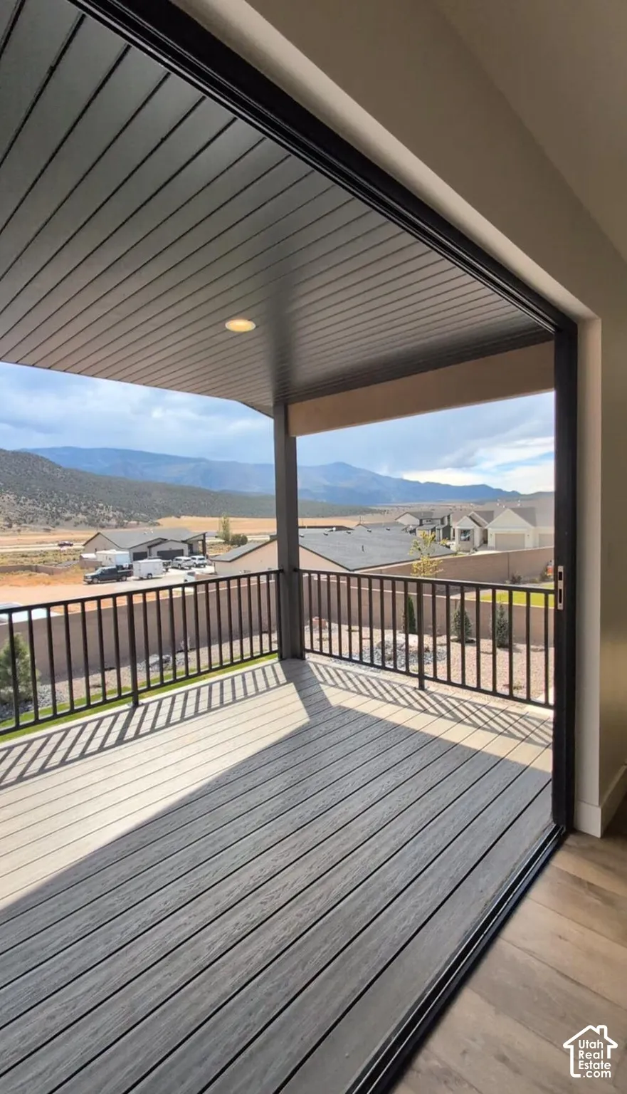 Covered outdoor deck with composite decking, black metal railing, and recessed lighting