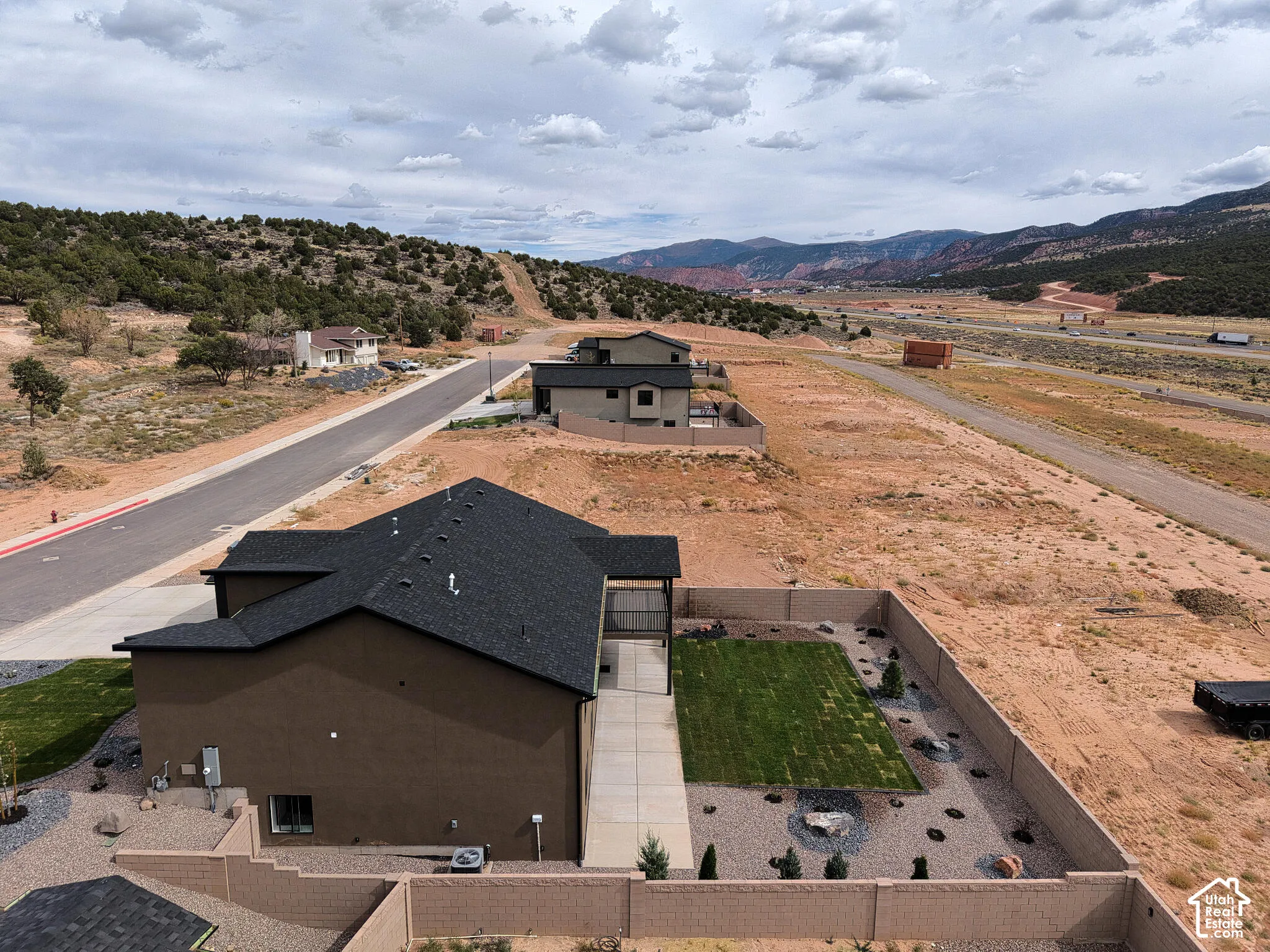 New construction with dark shingle roofing and an expansive backyard featuring a manicured lawn and decorative landscaping