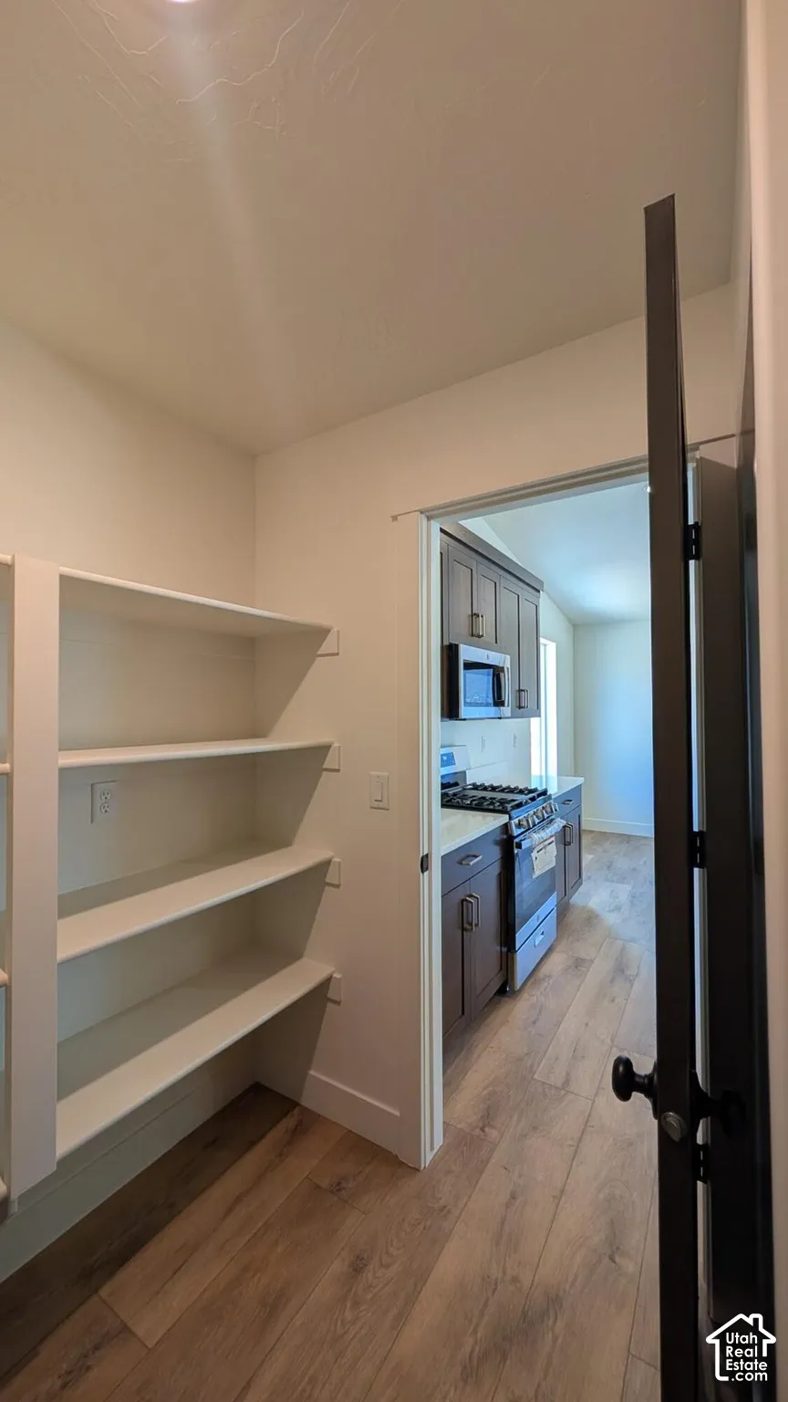 Built-in shelving for organized storage, wood-finish flooring, and a kitchen featuring dark wood cabinetry, stainless steel appliances, and a gas range