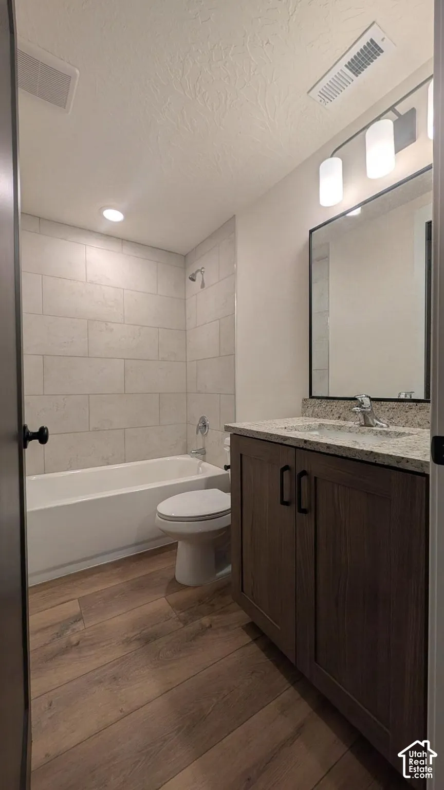 Wood-finish flooring with a vanity featuring a light-toned countertop, modern cabinetry, and a rectangular mirror