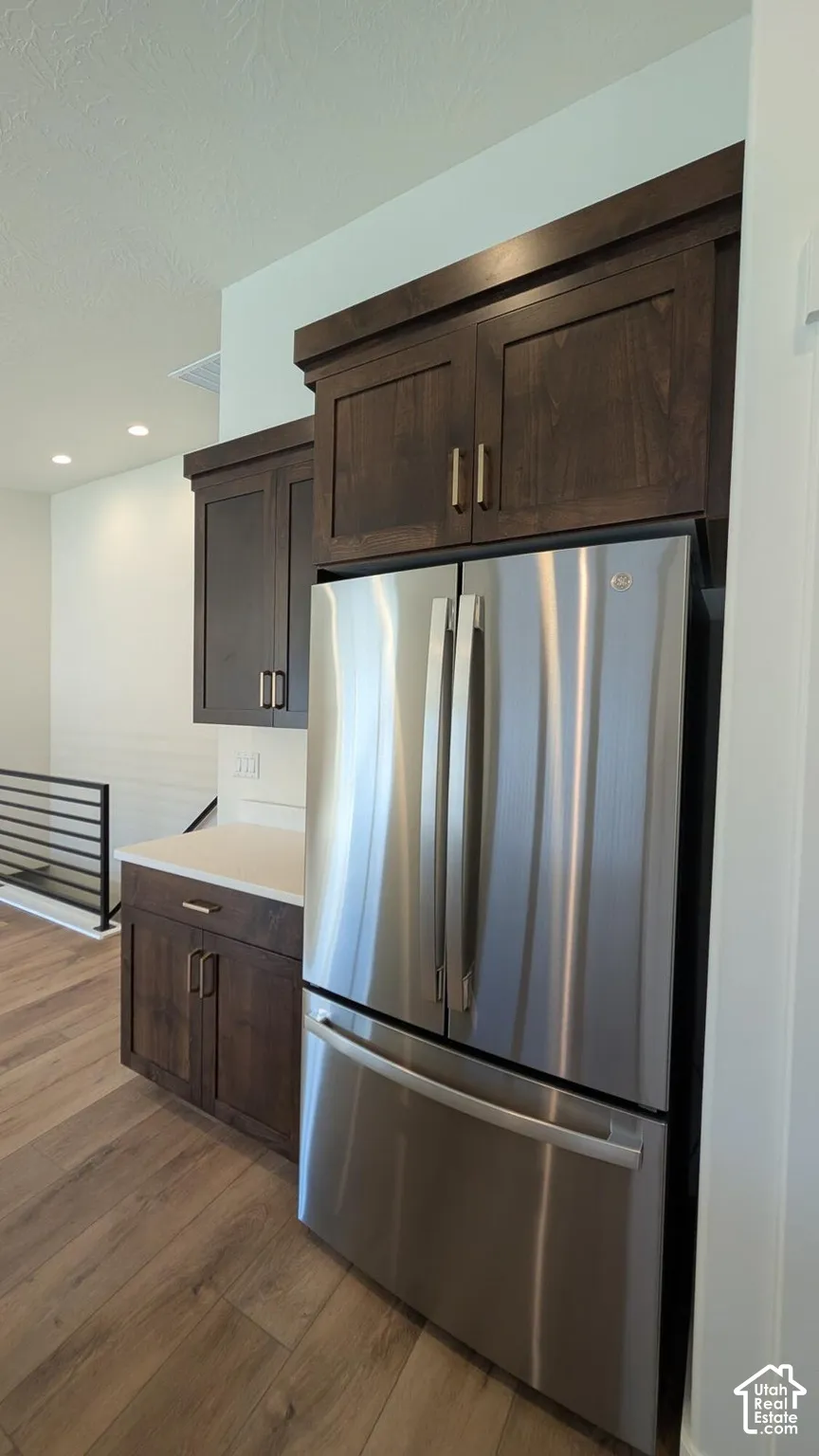 Stainless steel refrigerator integrated with dark wood-finish cabinetry and light-toned countertops
