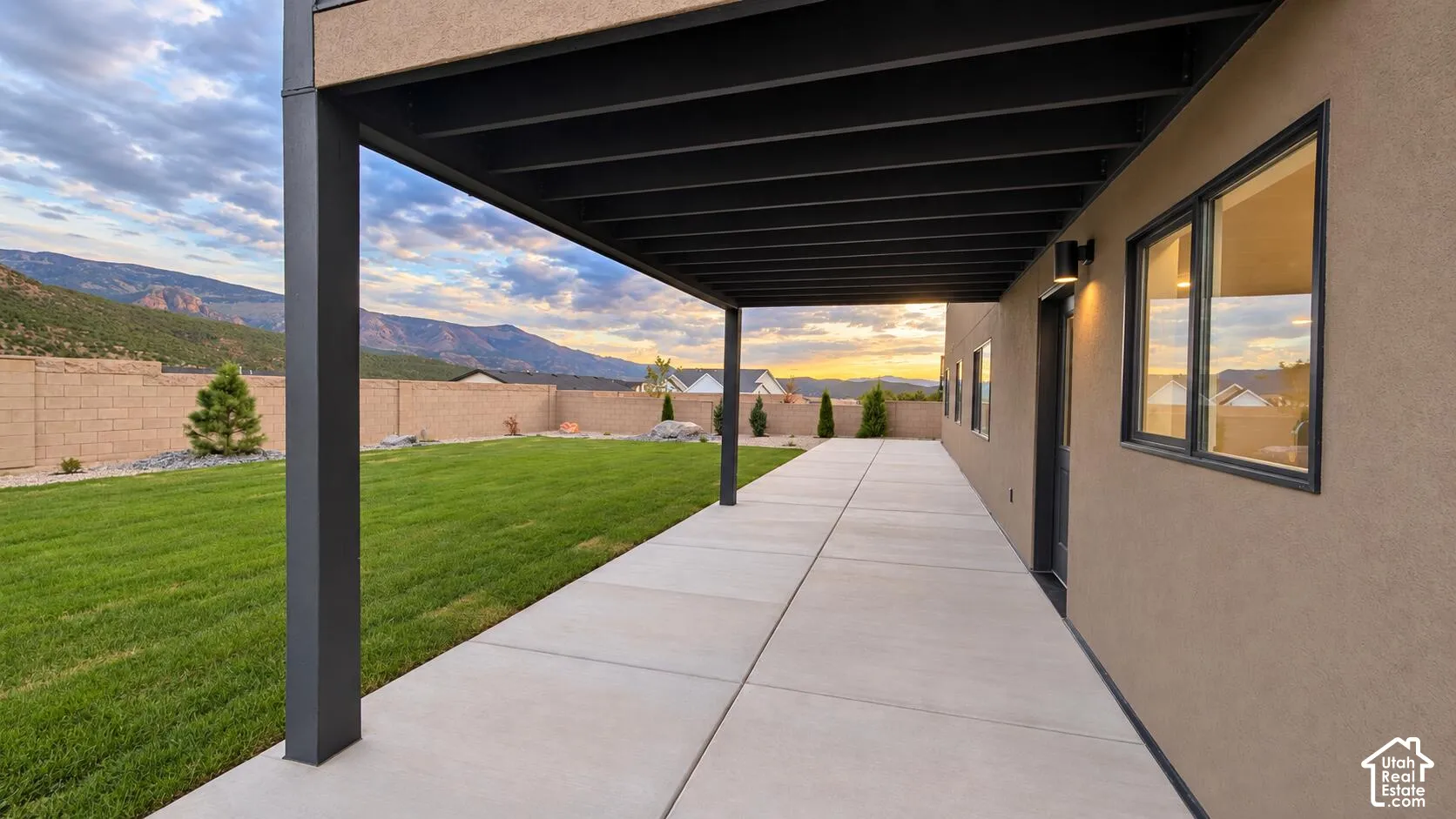 Covered patio with concrete slab, stucco exterior, and black-framed windows