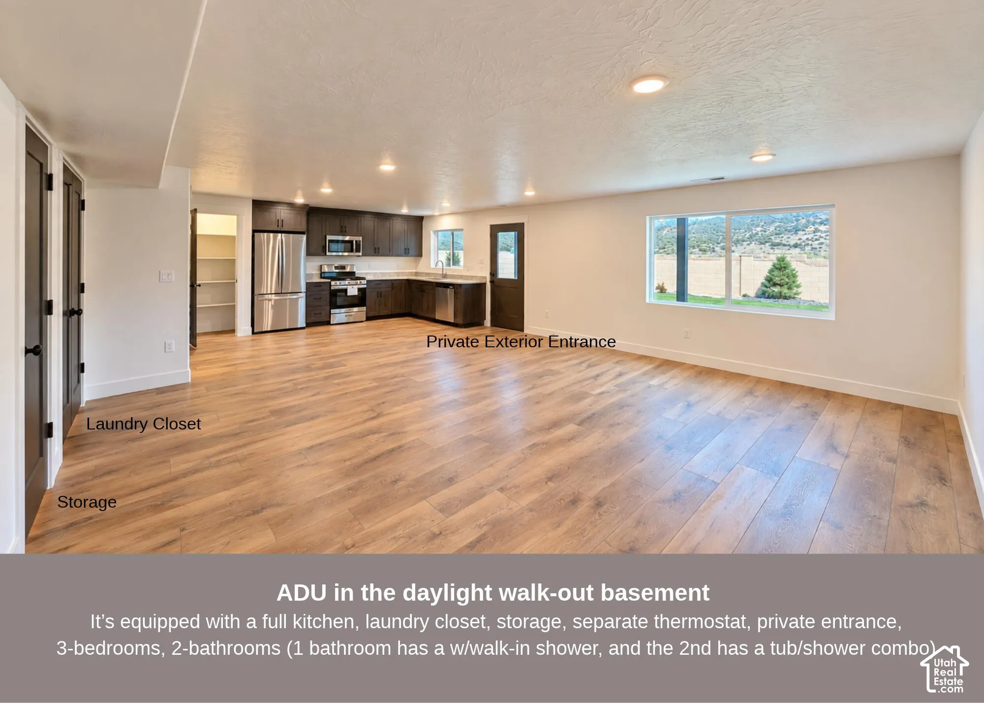 Open-concept living space featuring wood-finish flooring, recessed lighting, a full kitchen with stainless steel appliances, and a dedicated laundry closet