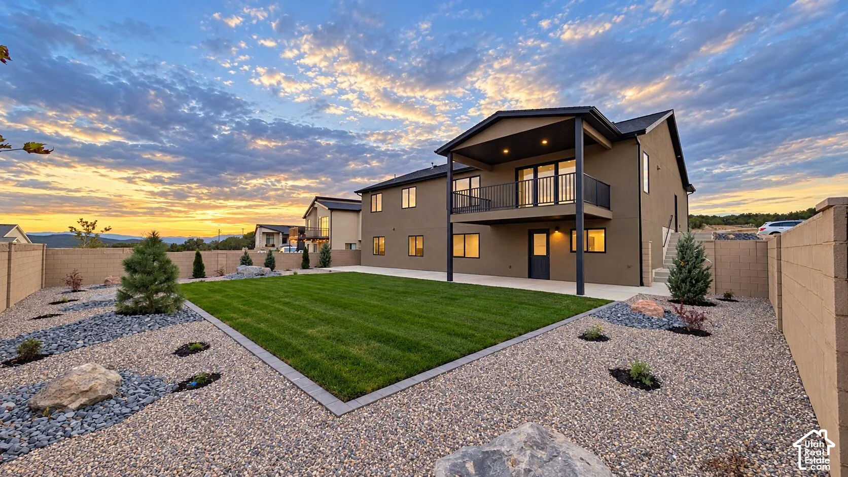 Expansive backyard featuring a manicured lawn, gravel landscaping with accent boulders, and mature plantings