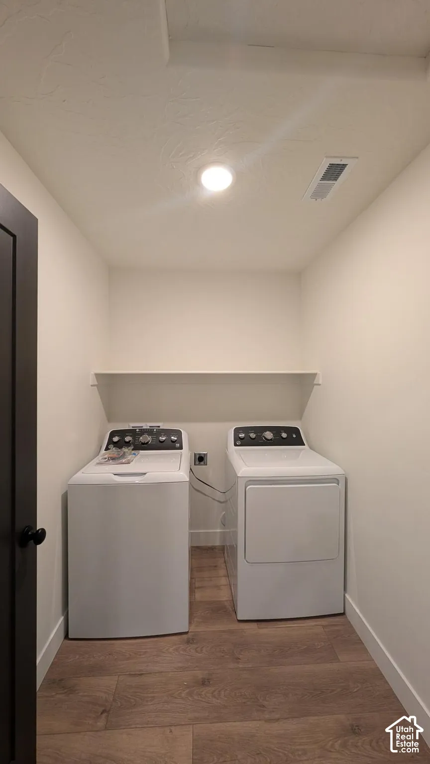 Wood-finish flooring with white baseboards, recessed ceiling lighting, and a wall-mounted storage shelf