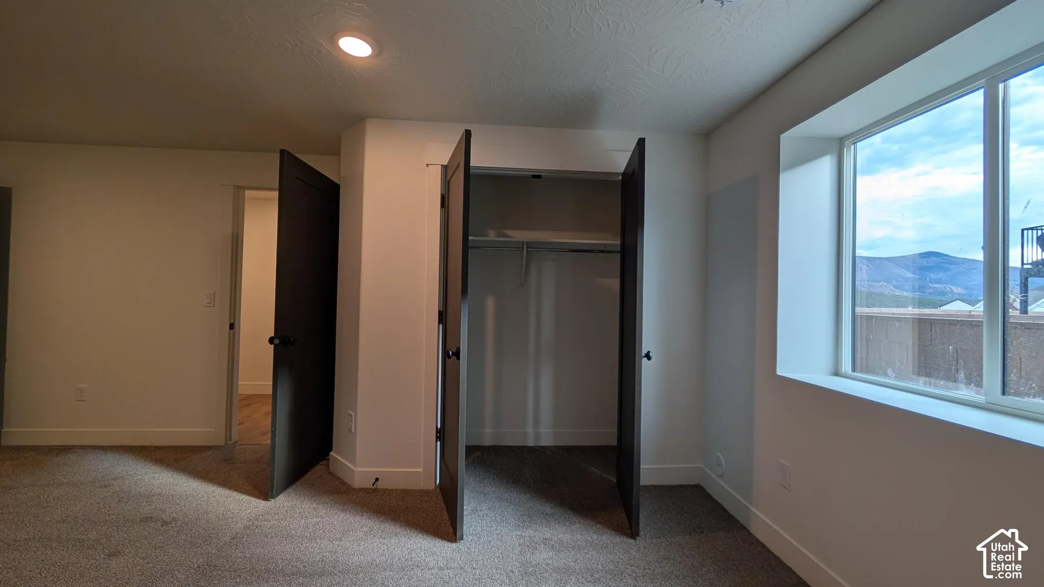 Neutral wall paint, recessed lighting, carpet flooring, large window, and mountain scenery