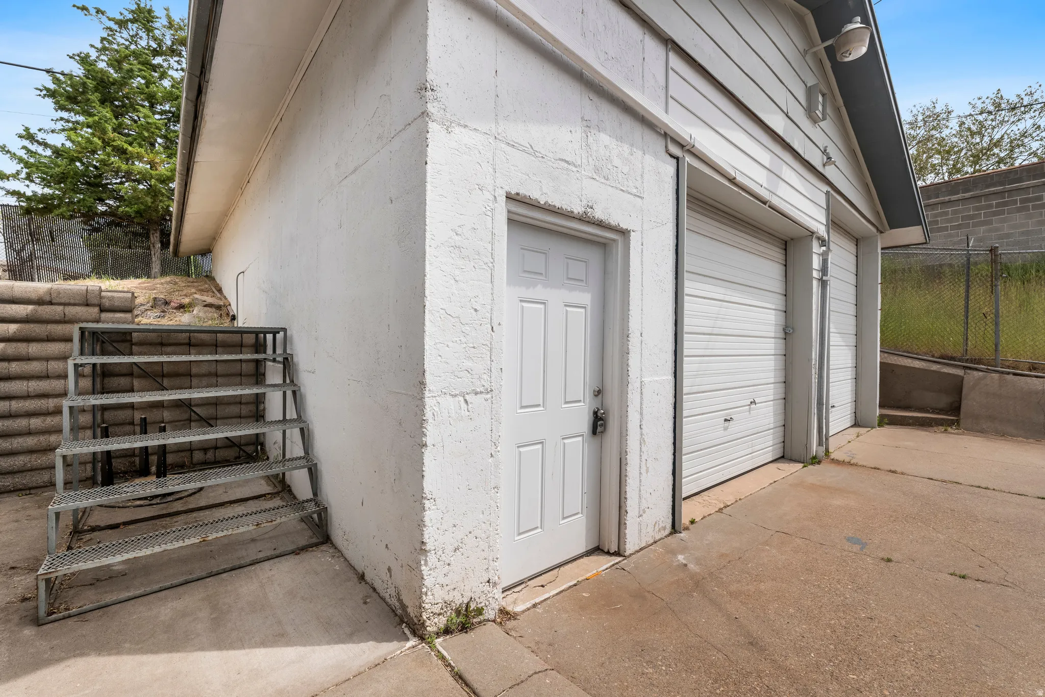 Two separate garage doors and an additional entry door are featured on this concrete and siding exterior