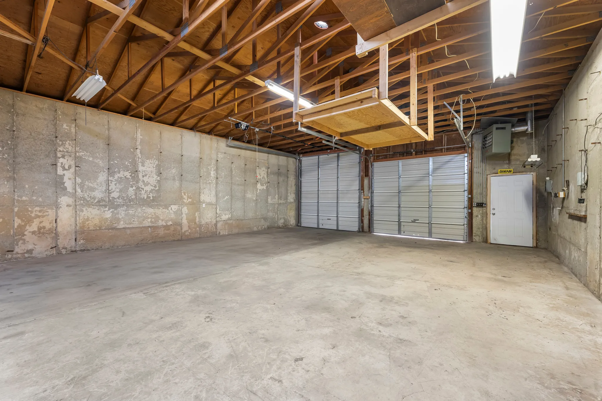 Spacious garage with exposed wood rafters and concrete flooring