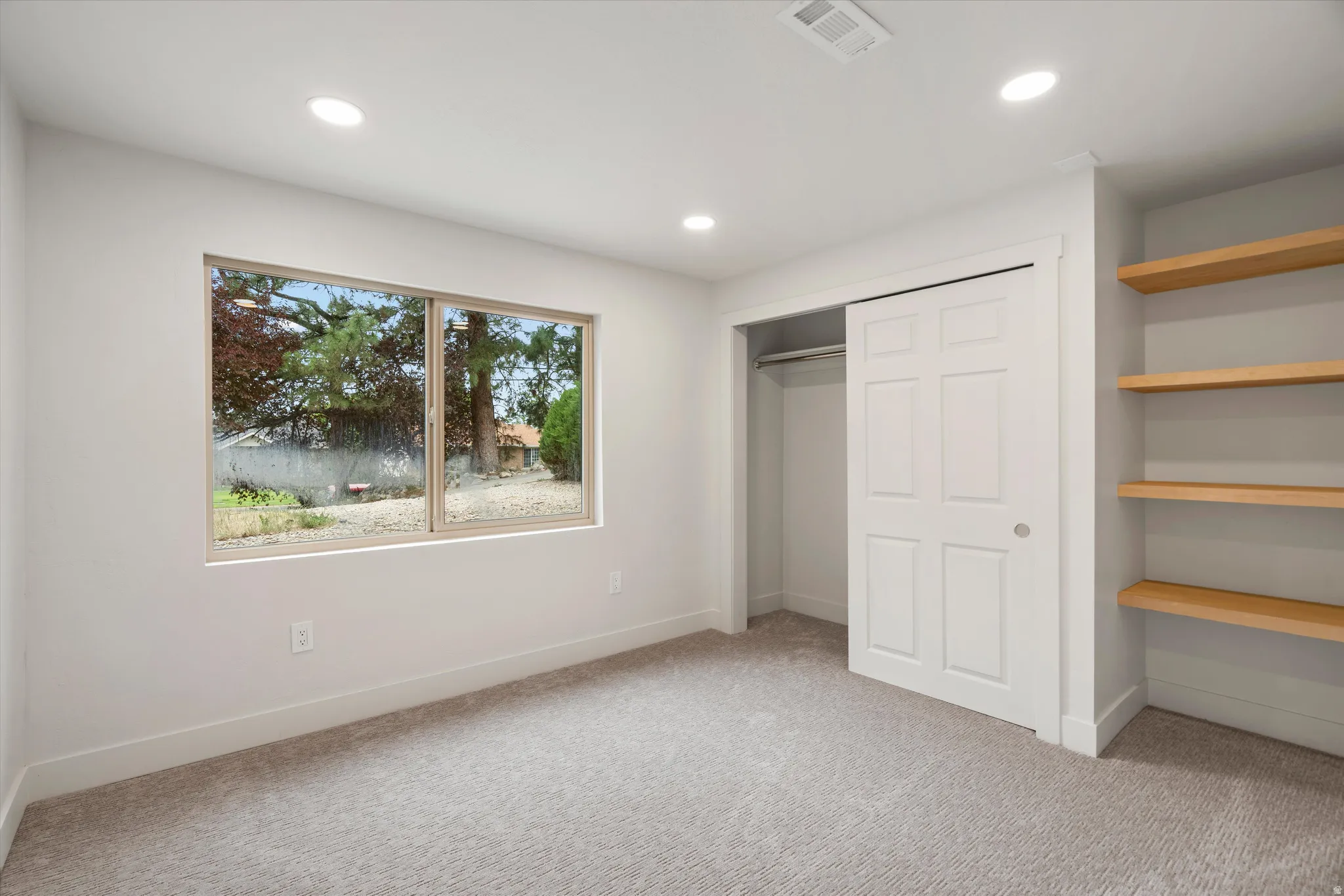 Bedroom featuring a wide window, built-in shelving, recessed lighting, and carpet flooring