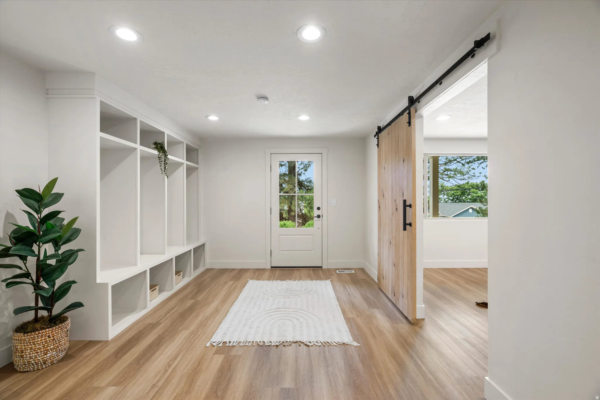 Entryway featuring built-in white cubby storage, wood-finish flooring, and a glass-paned exterior door