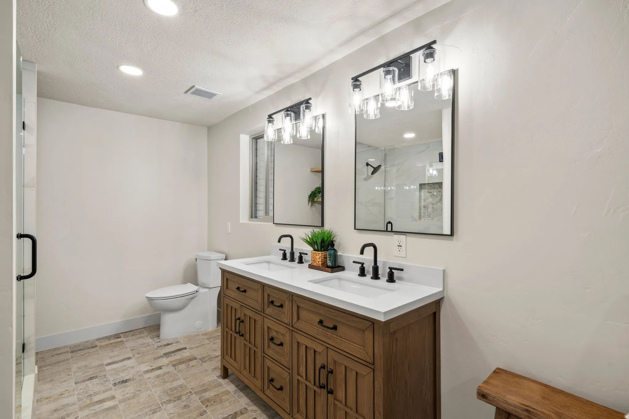 Dual vanity featuring a wood-finish cabinet, white countertops, and matte black fixtures