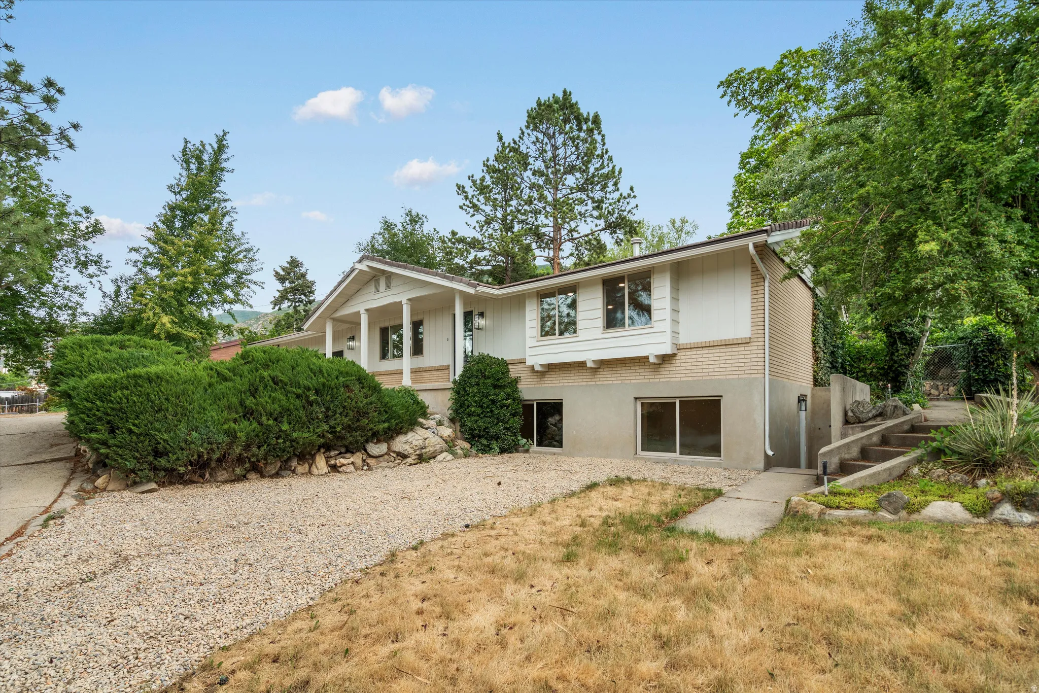 Separate Entrance to Basement Split-level residence featuring a covered front porch and a gravel driveway
