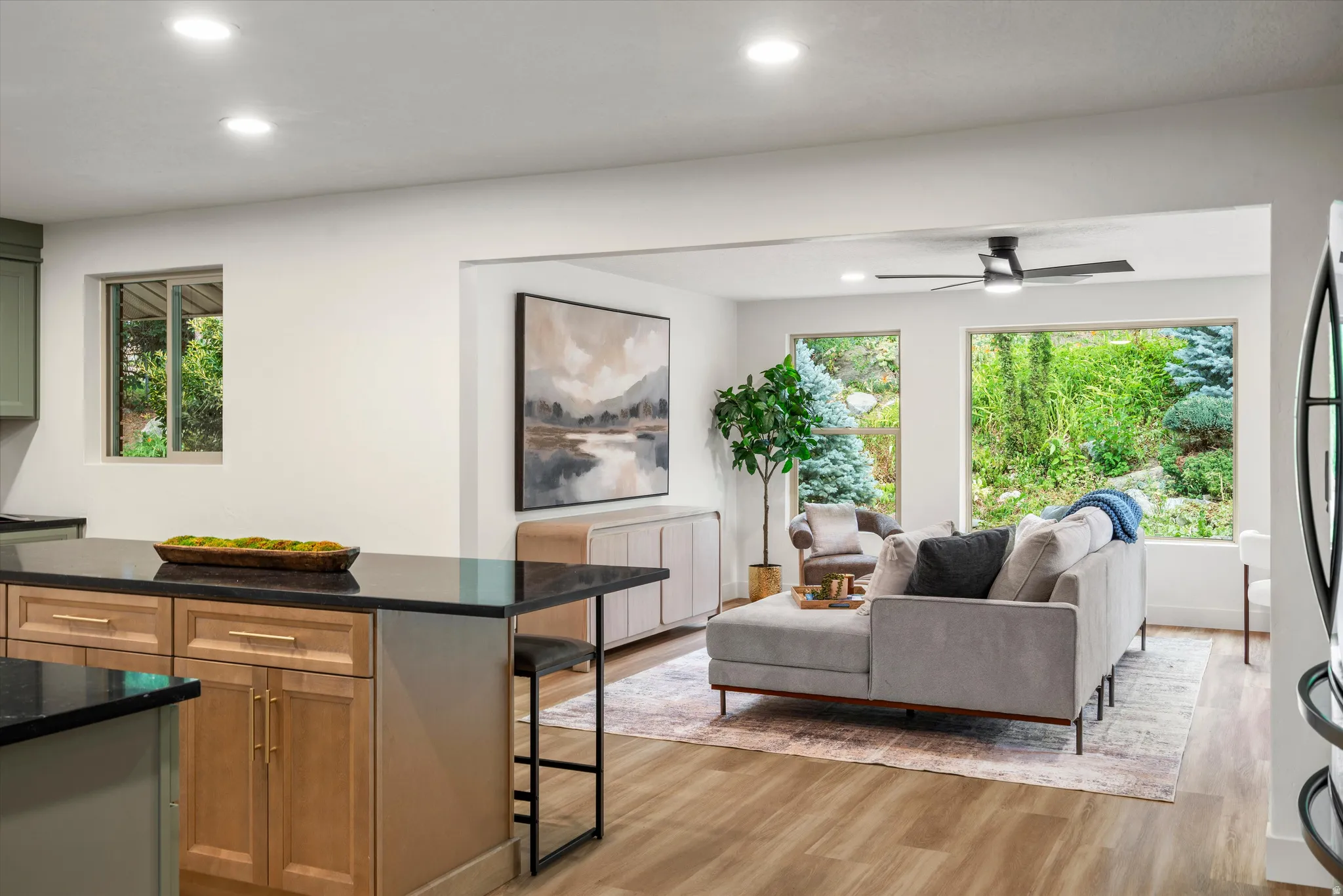 Kitchen island with black countertop and light wood cabinetry, featuring integrated seating