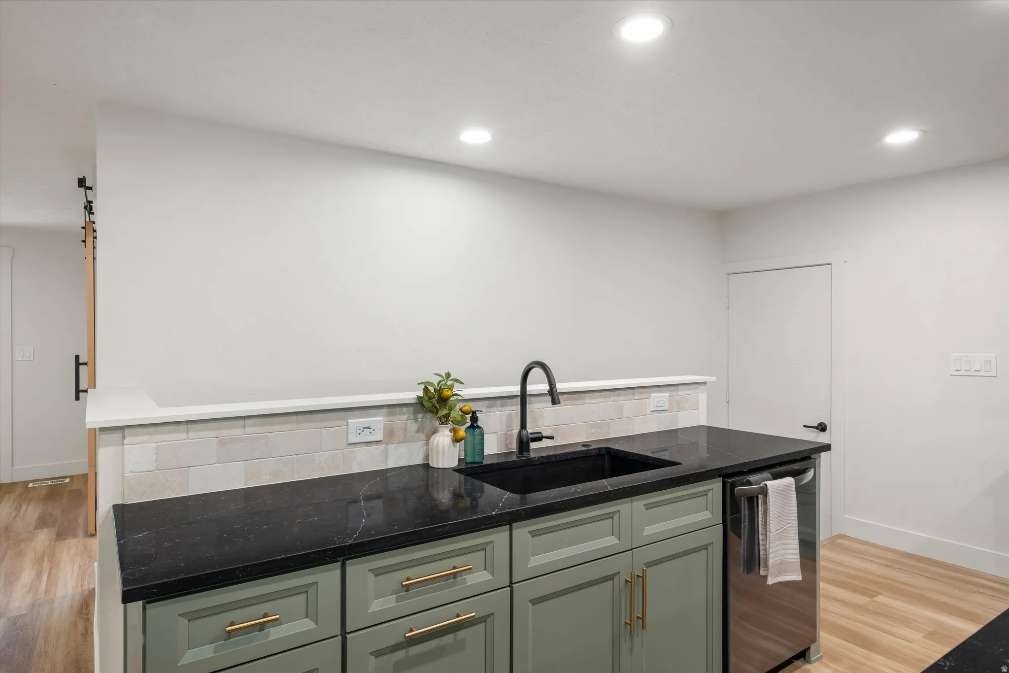 Kitchen island featuring a black sink, matte black faucet, and dark countertops