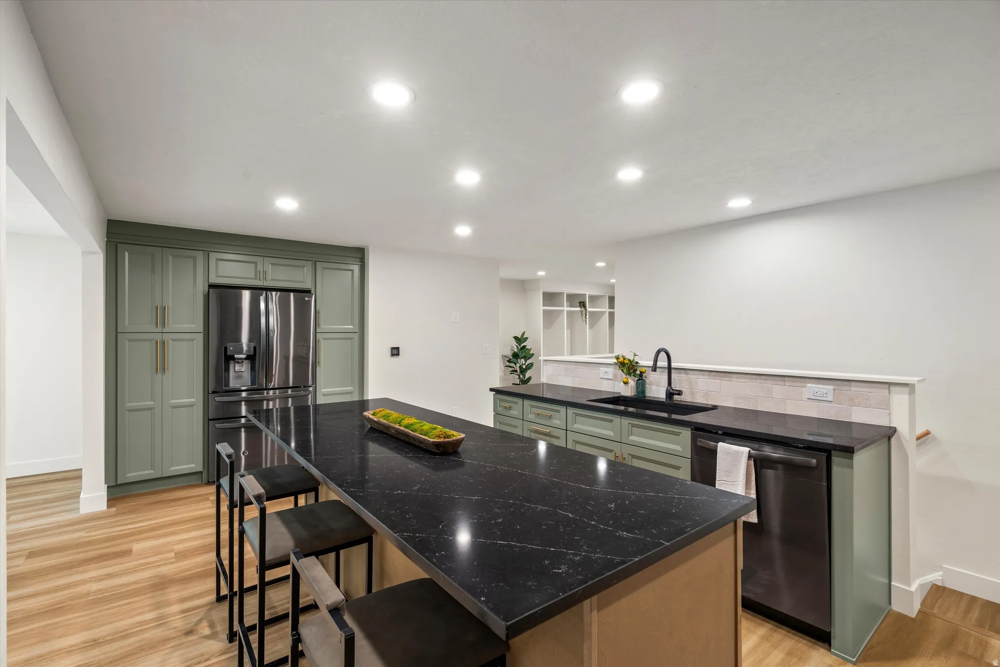 Kitchen featuring a large island with dark stone countertops, wood-finish flooring, recessed lighting, and sage green cabinetry