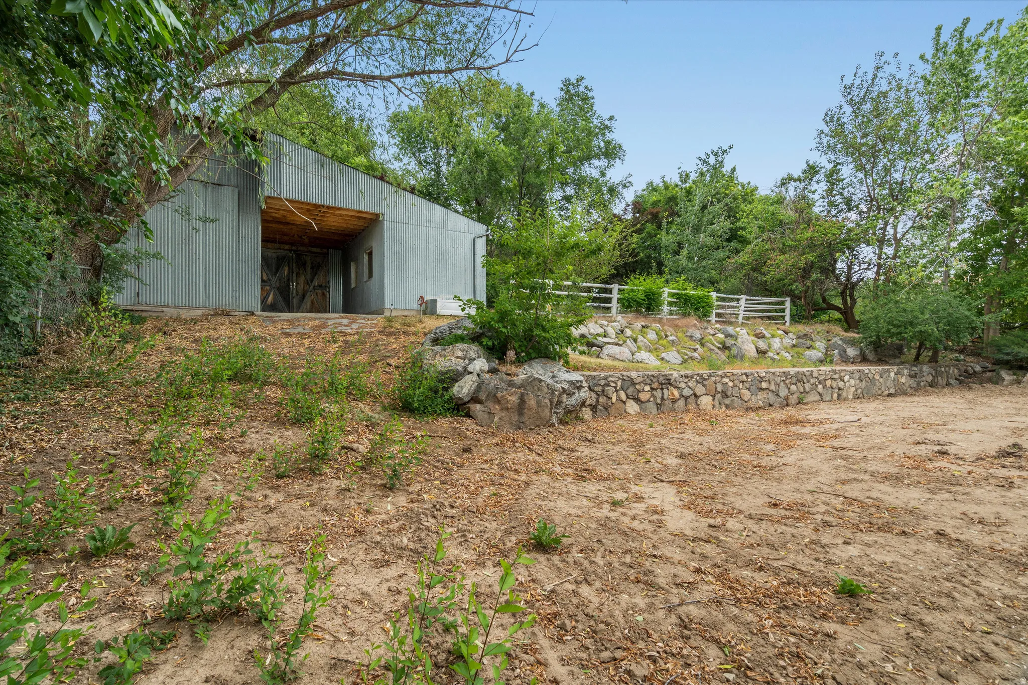Corrugated metal barn with a deep wood-clad overhang and large double doors