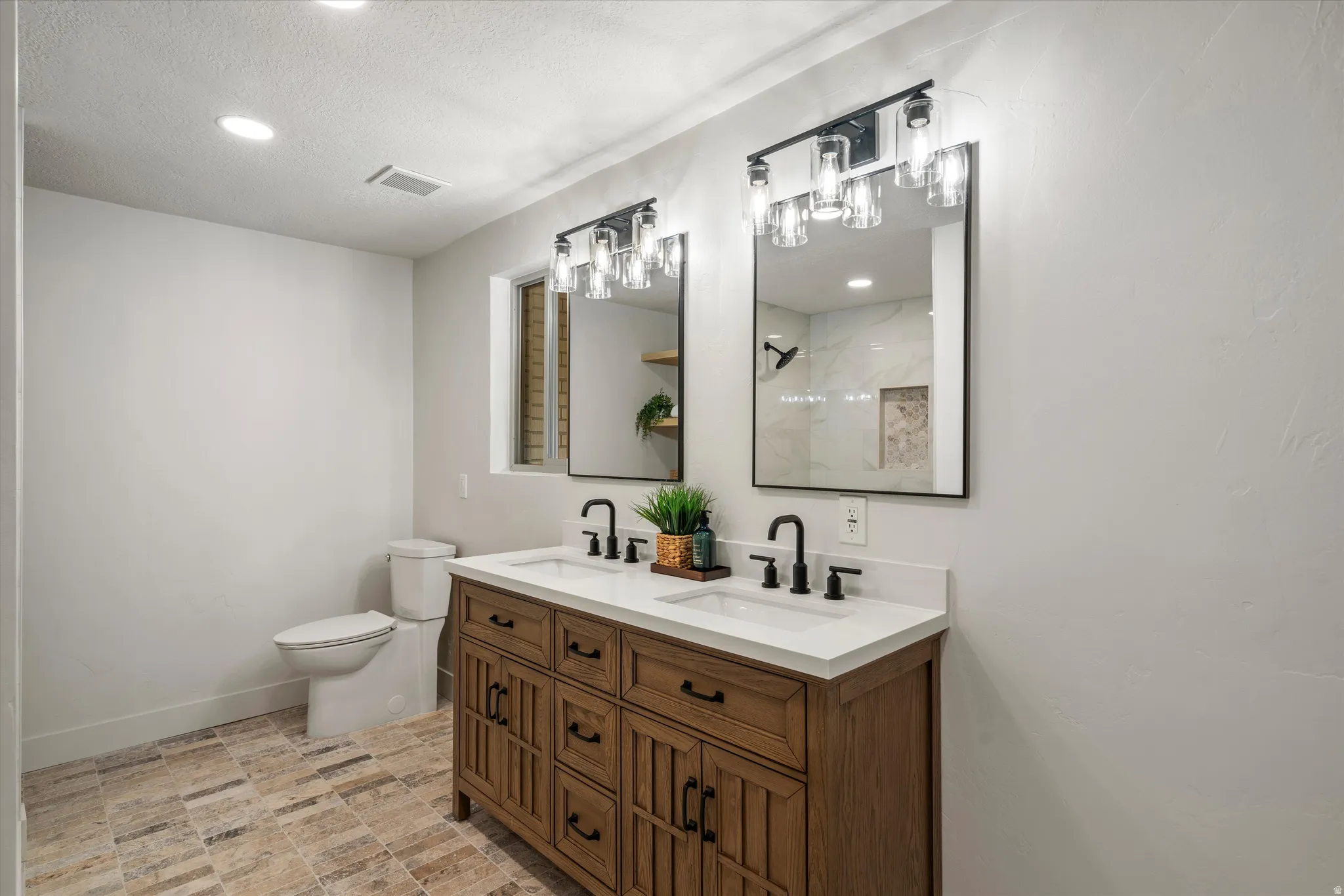 Double vanity featuring a wood-finish cabinet, white countertops, and matte black fixtures