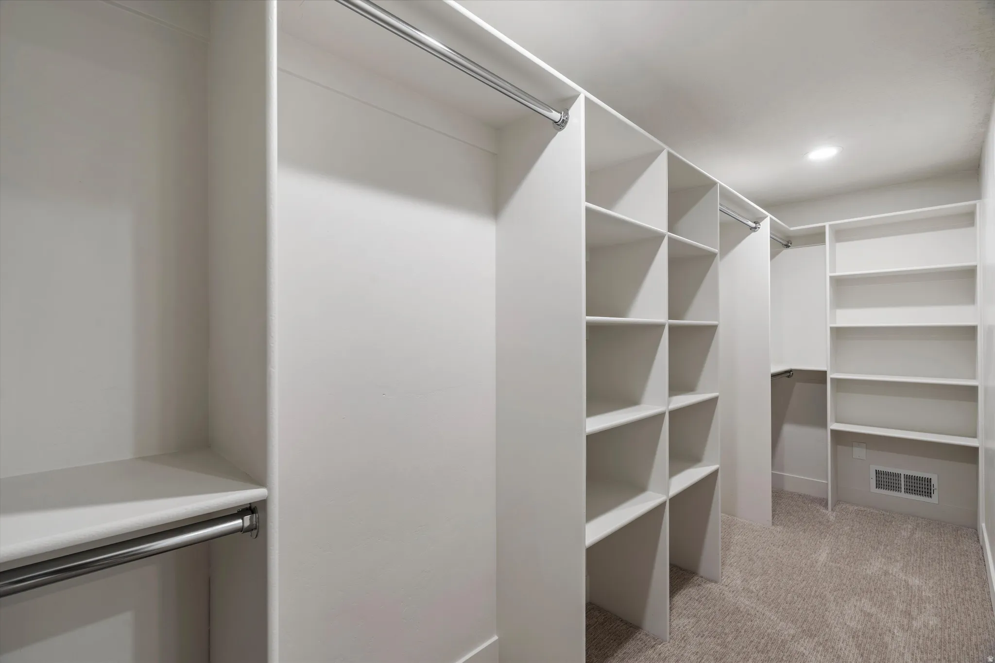 Primary Walk-in closet featuring built-in shelving, hanging rods, recessed lighting, and carpet flooring