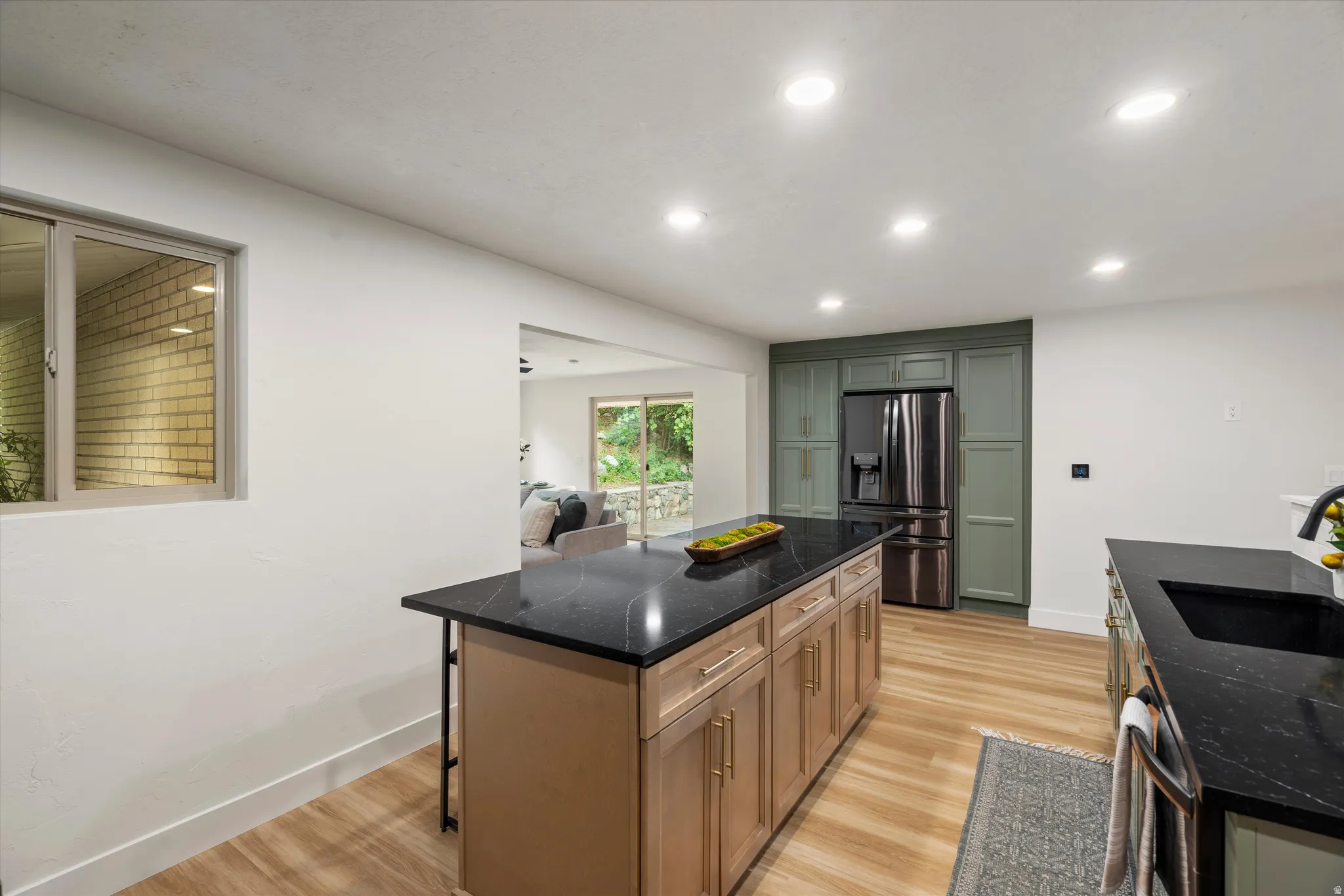 Modern kitchen featuring a central island with natural wood cabinetry and a dark countertop