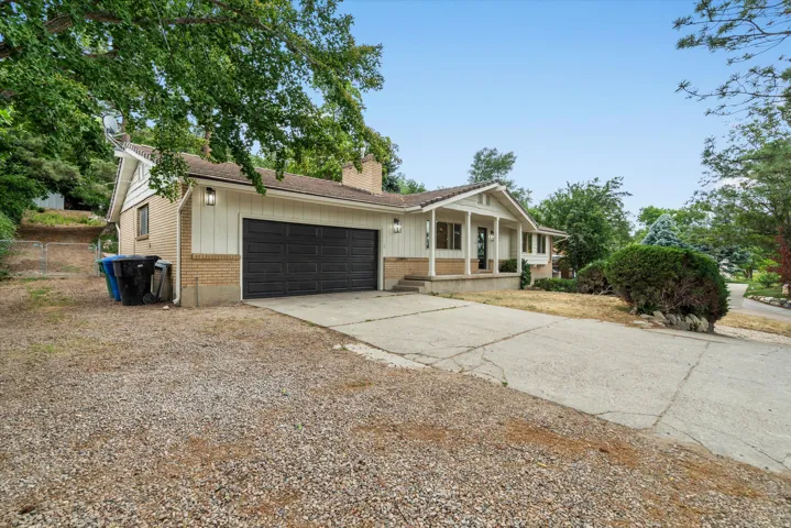 Ranch-style exterior with a two-car garage, brick facade, and white vertical siding