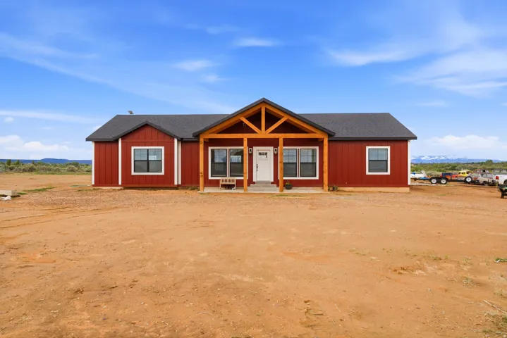 Red siding exterior with white trim, dark gray architectural shingle roof, and a covered entry featuring exposed wood beams